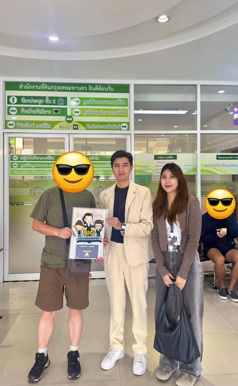 ผู้ซื้อและทีมงานถือเอกสารกรรมสิทธิ์ในโถงสำนักงานที่ดินกรุงเทพมหานคร